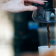Barista's hand dispensing coffee from drip machine